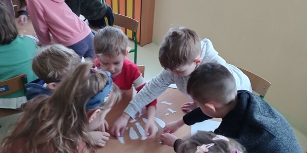 Dzieci układające papierowe kości dinozaura