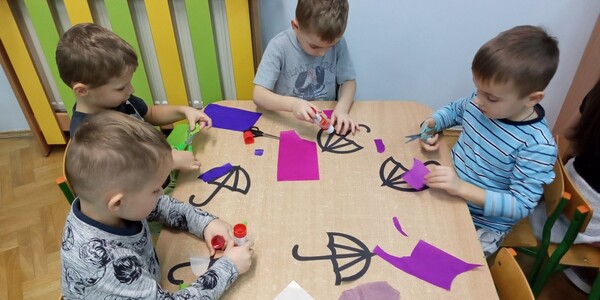 Dzieci wykonujące papierowy witraż w kształcie parasola