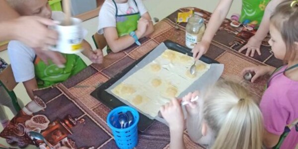 Dzieci nakładają konfitury na ciasto francuskie.