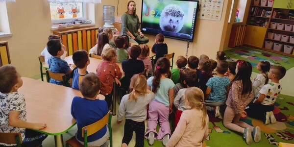 Dzieci słuchają opowiadania nauczycielki na temat jeża.