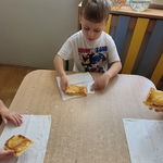 Chłopiec siedzi przy stoliku i je upieczone ciastko z jabłkami..jpg