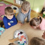 Grupa dzieci przygląda się kolorowej pianie powstającej podczas doświadczenia z sodą_ octem i barwnikami..jpg