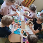Dzieci siedzą przy stoliku i w wielkim skupieniu malują farbami..jpg