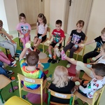 Dzieci siedzą na krzesełkach w kole. Na hasło; koło żółte_ podnoszą odpowiednią kończynę..jpg
