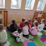Dzieci siedzą w parach na dywanie. Osoba siedząca z tyłu rysuje na plecach kolegi wybrany wzór..jpg