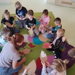Dzieci siedzą na dywanie. Każde dziecko podejmuje probę samodzielnego szycia..jpg