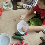Dzieci przygotowują warzywa do sałatki. Rozdzielają liście sałaty i wkładają je do miseczek.jpg